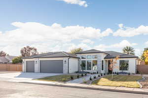 View of front facade featuring driveway, a tiled roof, an attached garage, stucco siding, and stone siding