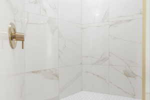Full bath featuring a marble finish shower