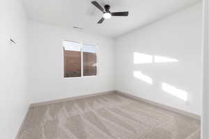 Carpeted spare room with baseboards and a ceiling fan