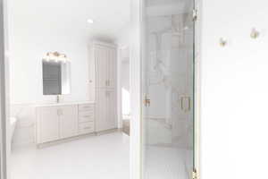 Bathroom featuring a marble finish shower, vanity, and recessed lighting