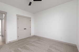 Unfurnished bedroom featuring light carpet, a closet, and a ceiling fan