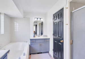 Full bath featuring vanity, a bath, a stall shower, and light wood-style floors