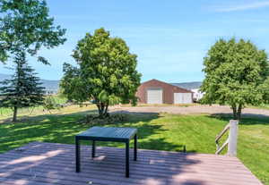 Wooden terrace featuring an outdoor structure, a yard, a pole building, and a mountain view