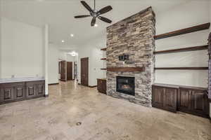 Unfurnished living room featuring ceiling fan, a fireplace, recessed lighting, and stone tile floors