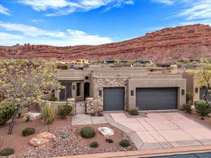 Adobe home with stucco siding, driveway, a mountain view, and an attached garage