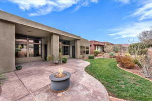 Rear view of property featuring a fire pit, stucco siding, and a lawn