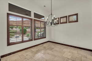 Spare room with stone tile flooring and a chandelier