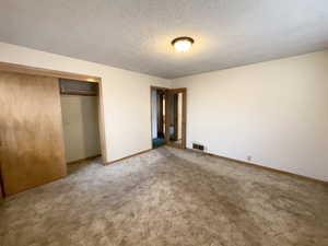 Unfurnished bedroom with a textured ceiling, a closet, and carpet flooring