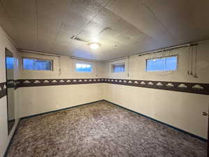 Empty room featuring dark colored carpet and baseboards