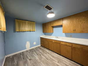 Kitchen with light countertops, brown cabinetry, and light wood-type flooring
