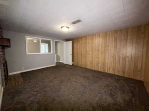 Unfurnished living room with wood walls and dark carpet