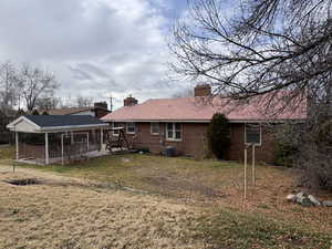 Back of house featuring a chimney, a lawn, and brick siding