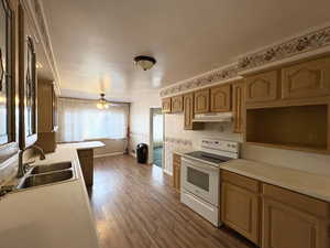 Kitchen with white range with electric stovetop, wallpapered walls, light countertops, a ceiling fan, and dark wood-type flooring