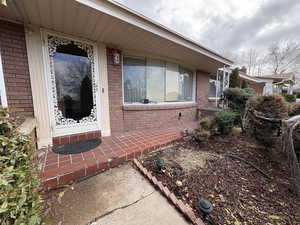 Doorway to property featuring brick siding and covered porch