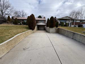 View of front facade featuring a front lawn, concrete driveway, and a garage