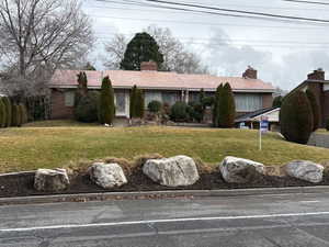 Ranch-style home featuring brick siding, a chimney, and a front yard