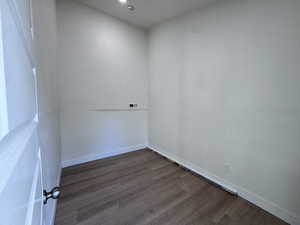 Empty room featuring dark wood-style flooring and baseboards