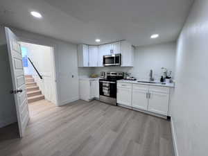 Kitchen featuring stainless steel appliances, white cabinets, light wood-style floors, and recessed lighting