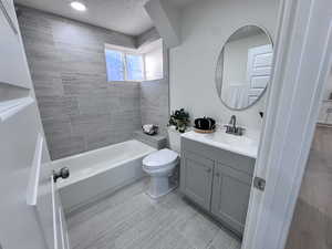 Bathroom with vanity, a textured ceiling, and tub / shower combination
