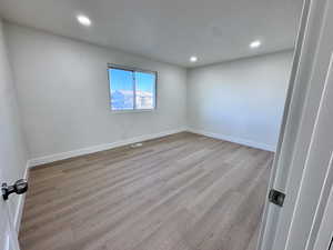 Empty room featuring light wood-style floors and recessed lighting