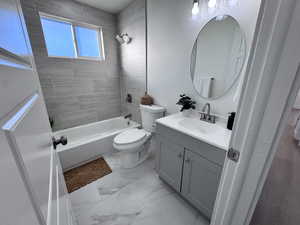 Bathroom featuring vanity, shower / bath combination, and light marble finish floors