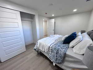 Bedroom featuring light wood finished floors, a closet, and recessed lighting