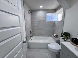 Full bathroom with a textured ceiling, vanity, and washtub / shower combination