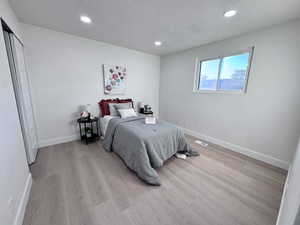 Bedroom featuring a textured ceiling, recessed lighting, light wood-type flooring, and a closet