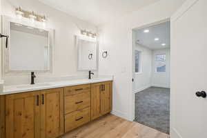 Full bath with double vanity, light wood-style flooring, and recessed lighting