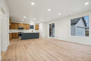 Kitchen featuring open floor plan, light countertops, light wood-type flooring, an island with sink, and recessed lighting