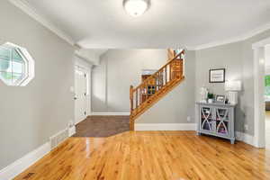 Entrance foyer featuring stairs, hardwood / wood-style floors, and ornamental molding