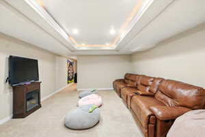 Living room featuring light carpet, a tray ceiling, ornamental molding, and recessed lighting