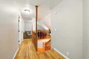 Hallway featuring attic access, light wood finished floors, and an upstairs landing