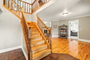 Stairway featuring ornamental molding and wood finished floors