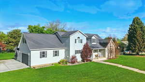 View of front of home featuring a front yard, covered porch, concrete driveway, and a shingled roof