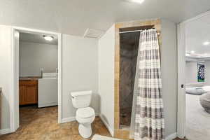 Bathroom featuring washer / clothes dryer, a stall shower, a textured ceiling, and connected bathroom