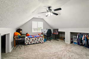 Bedroom with carpet, a textured ceiling, ceiling fan, and lofted ceiling
