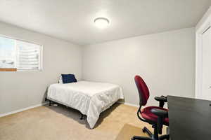 Carpeted bedroom with a textured ceiling and baseboards