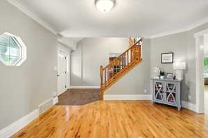 Foyer with stairway, hardwood / wood-style flooring, and ornamental molding