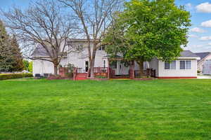 Rear view of house with a yard and a wooden deck