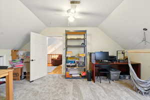 Office space featuring vaulted ceiling, light carpet, and a ceiling fan