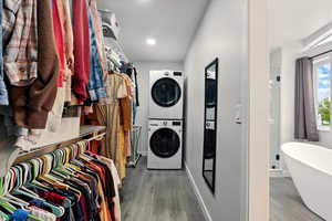 Washroom featuring stacked washer and clothes dryer and wood finished floors