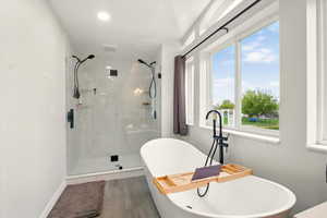 Bathroom featuring a freestanding tub and a marble finish shower