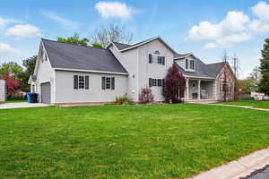 View of front of house with a porch, a front yard, roof with shingles, and concrete driveway