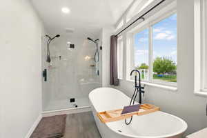 Bathroom featuring a freestanding tub and a marble finish shower