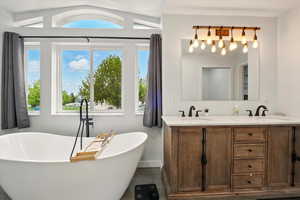 Full bathroom featuring double vanity, a soaking tub, and lofted ceiling