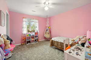 Carpeted bedroom with ceiling fan and baseboards