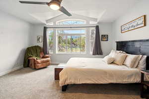 Carpeted bedroom with vaulted ceiling and ceiling fan