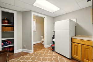 Kitchen with freestanding refrigerator, brown cabinets, and light countertops