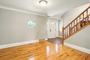 Entryway featuring stairs, hardwood / wood-style flooring, and ornamental molding